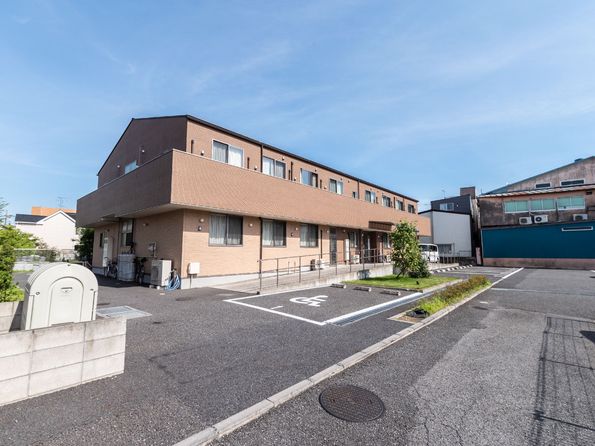 アスファルトに隣接しているベージュの外観で２階建ての建物