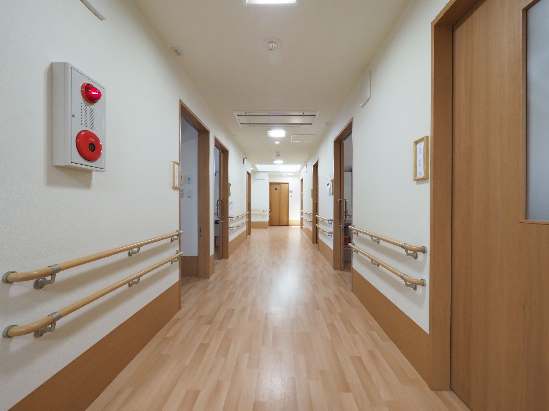 広々とした廊下の壁には両側に2段にわたって手摺りが設けられている。部屋のドアは使用しやすい引き戸になっている。