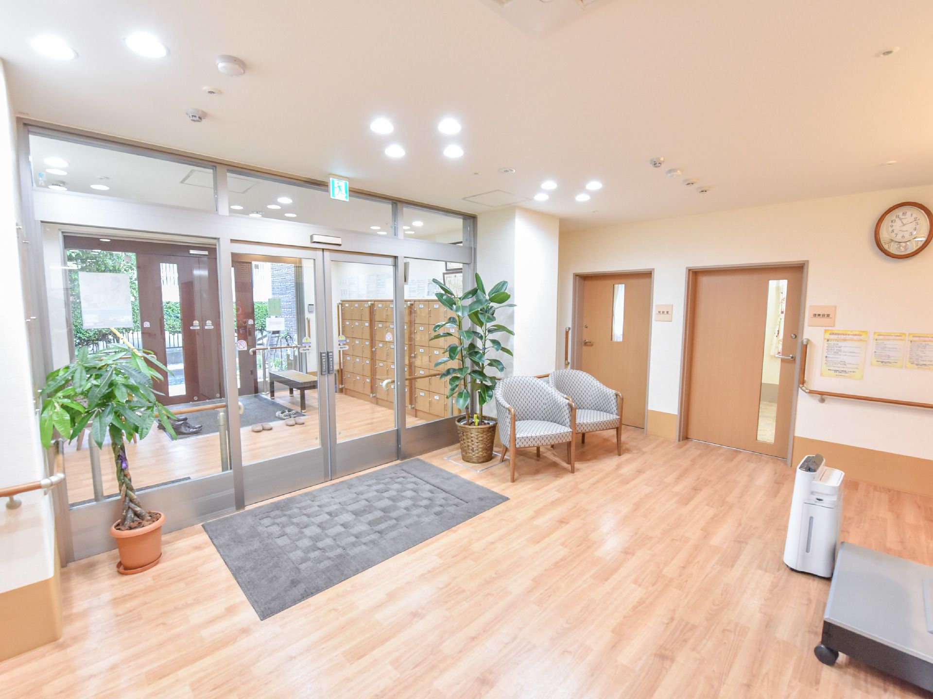 玄関ホールの床は一面フラットなフローリングである。入り口は両開きの自動ドアで、4面が大きなガラス張りとなっている。