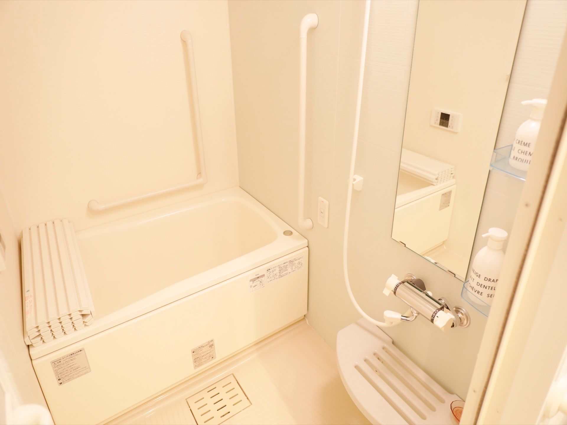 白色を基調とした個浴用の浴室で、壁には手すりや緊急時呼び出しベルが備わっている。洗い場には棚が設けられている。