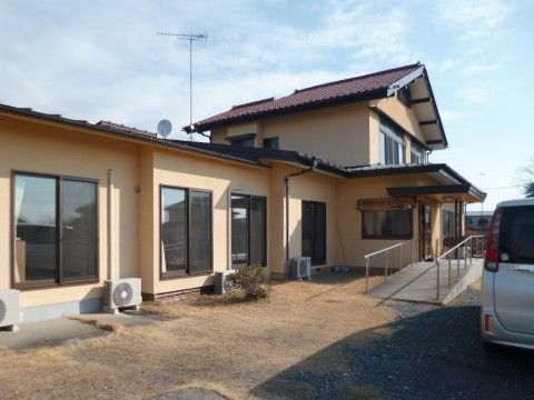 玄関までは手すり付きスロープがあり、平屋部分と2階建て部分がある間口が広い戸建て