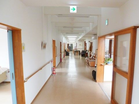 真っ白な壁に明るい茶色の建具と手すりがアクセントになっている長い廊下