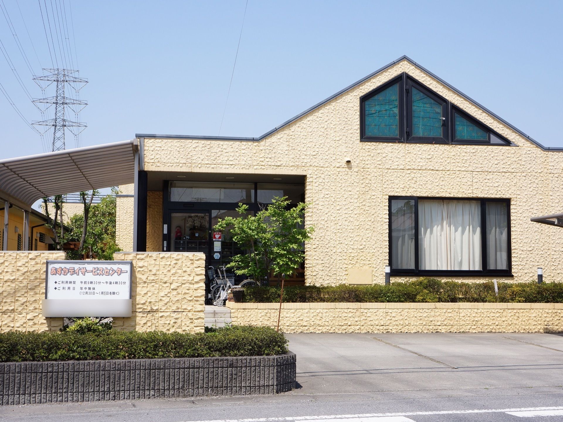 平屋建ての建物で、壁が白く三角屋根である。デイサービスセンターが併設されている。施設前に木が植えられている。