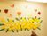 黄色と白色の花紙で作られた花畑の周りに、テントウムシやちょうちょの虫や、ウサギなどの動物たちの絵が飾られている。