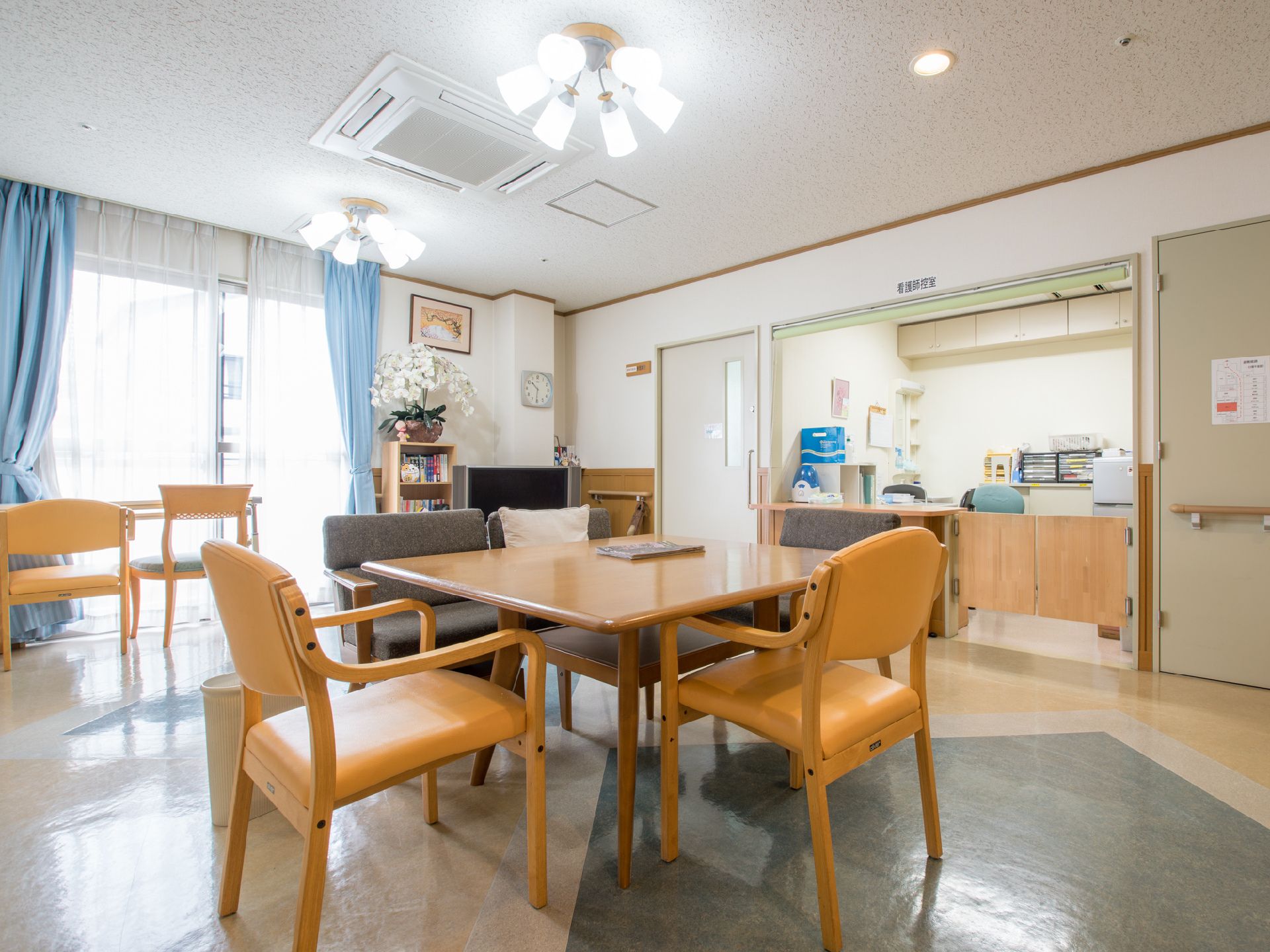 明るいオレンジのイスとブルーのカーテンがさわやかな食堂。