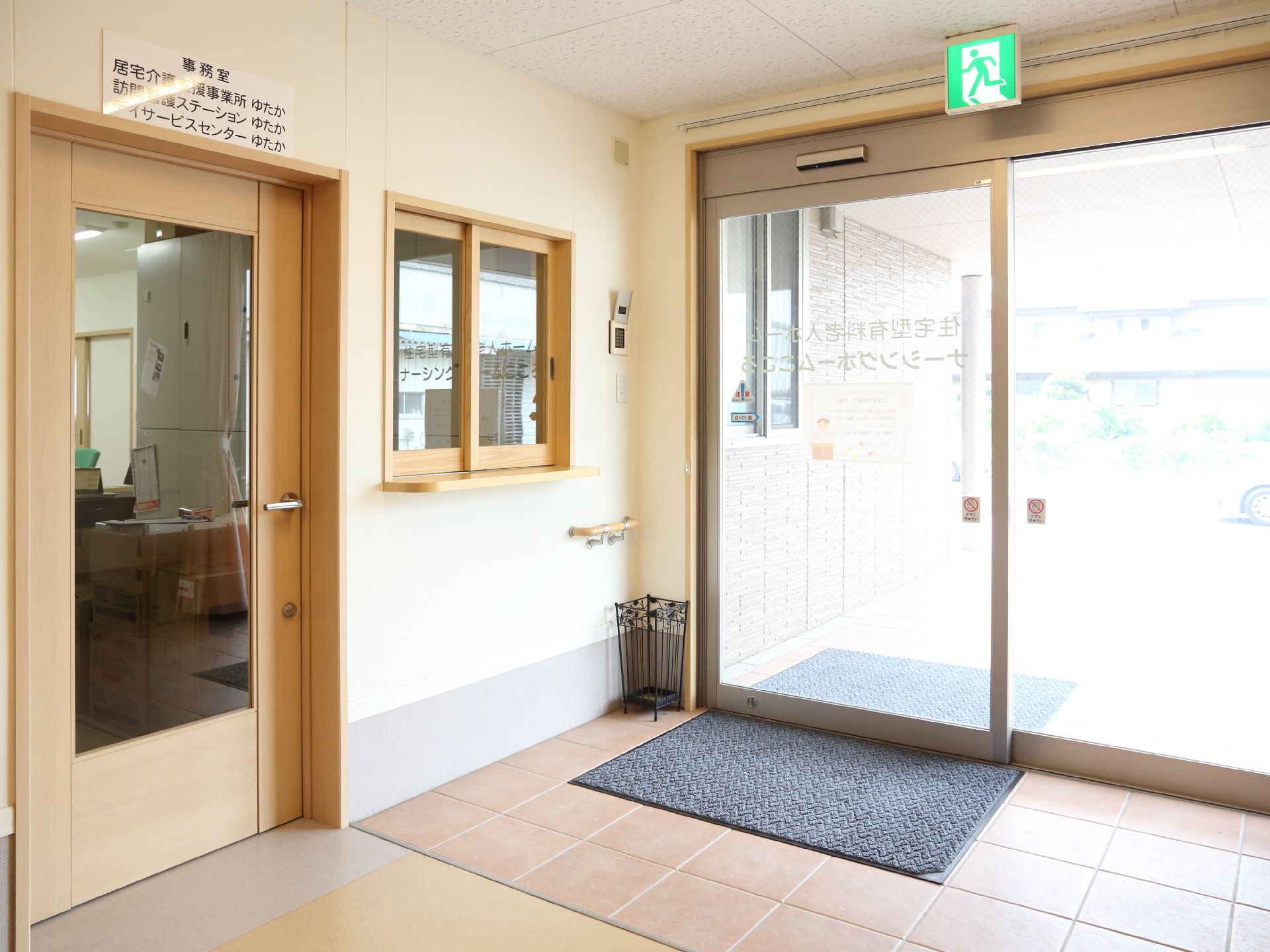 右側には外へと続く自動ドアがある。ドアの外側と内側にはマットが敷いてある。左側には扉や小窓があり、そこは事務室になっている。