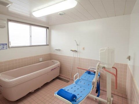 ピンク色のタイルと白い壁が明るい浴室には、シャワーキャリーを設置