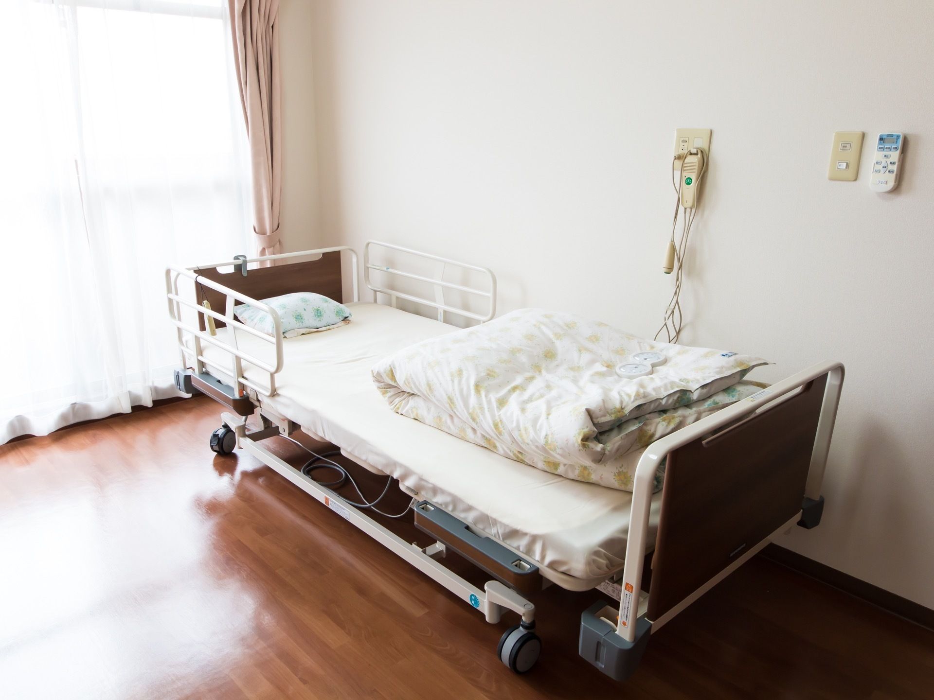 居室には大きな掃き出し窓があり、光が差しこんでとても明るい。転落防止柵のついた介護ベッドが設置されている。
