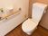 トイレの壁には横方向の手すりが設置されている。その上の方に、トイレットペーパーホルダーと緊急呼び出しボタンがついている。
