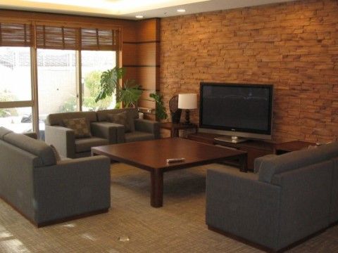 木目調の四角いテーブルに、グレーのソファーが置かれている。壁やブラインドなどが木の素材になっており、おしゃれで高級感のある空間になっている。
