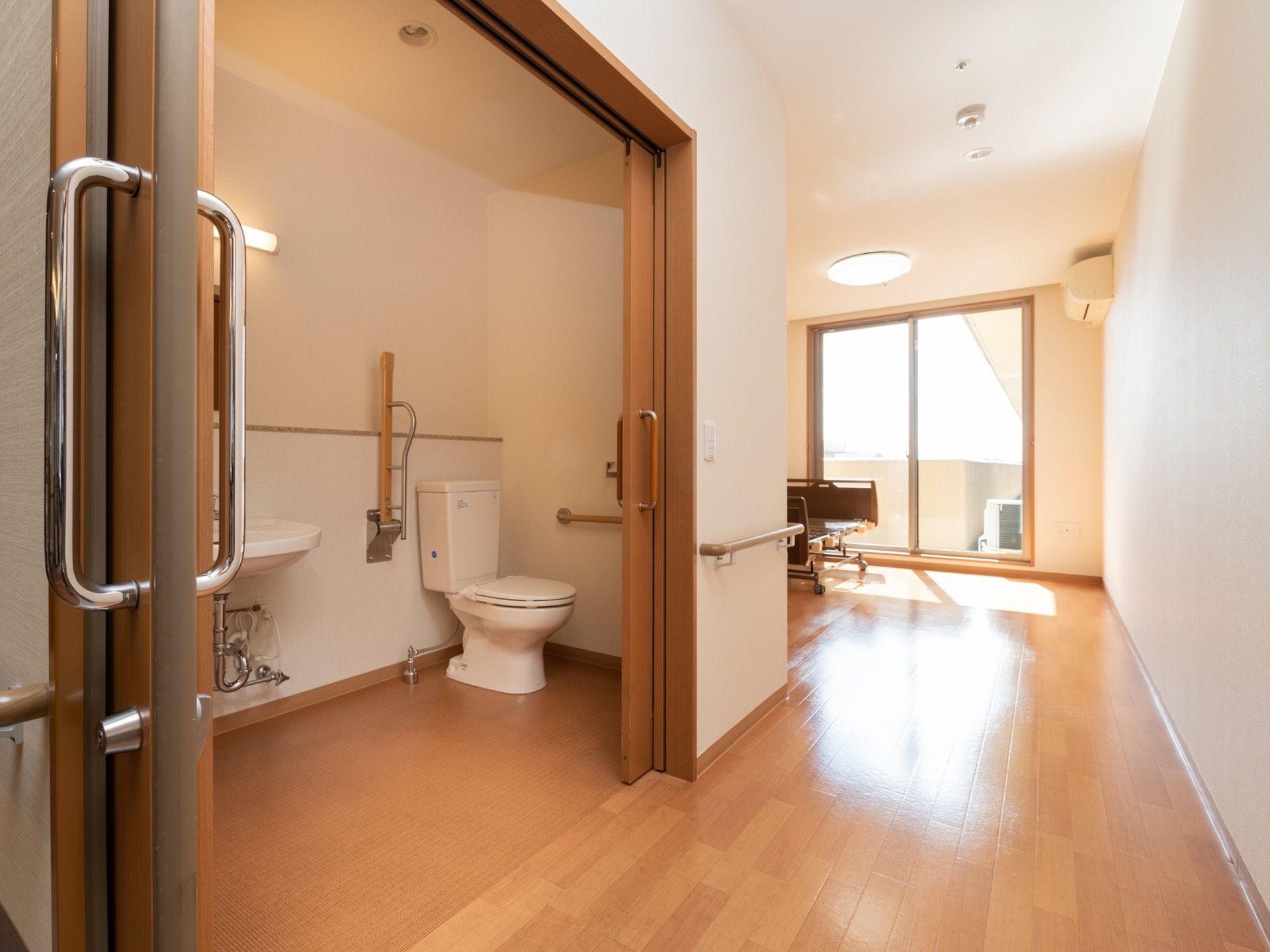 各居室の入り口付近には車椅子に乗ったまま入れるトイレがある。部屋の奥には窓があり、ベランダにも出ることができる。