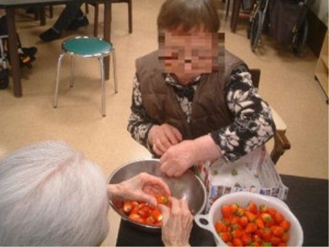 椅子に座りテーブルの上でイチゴのヘタをとる女性2人