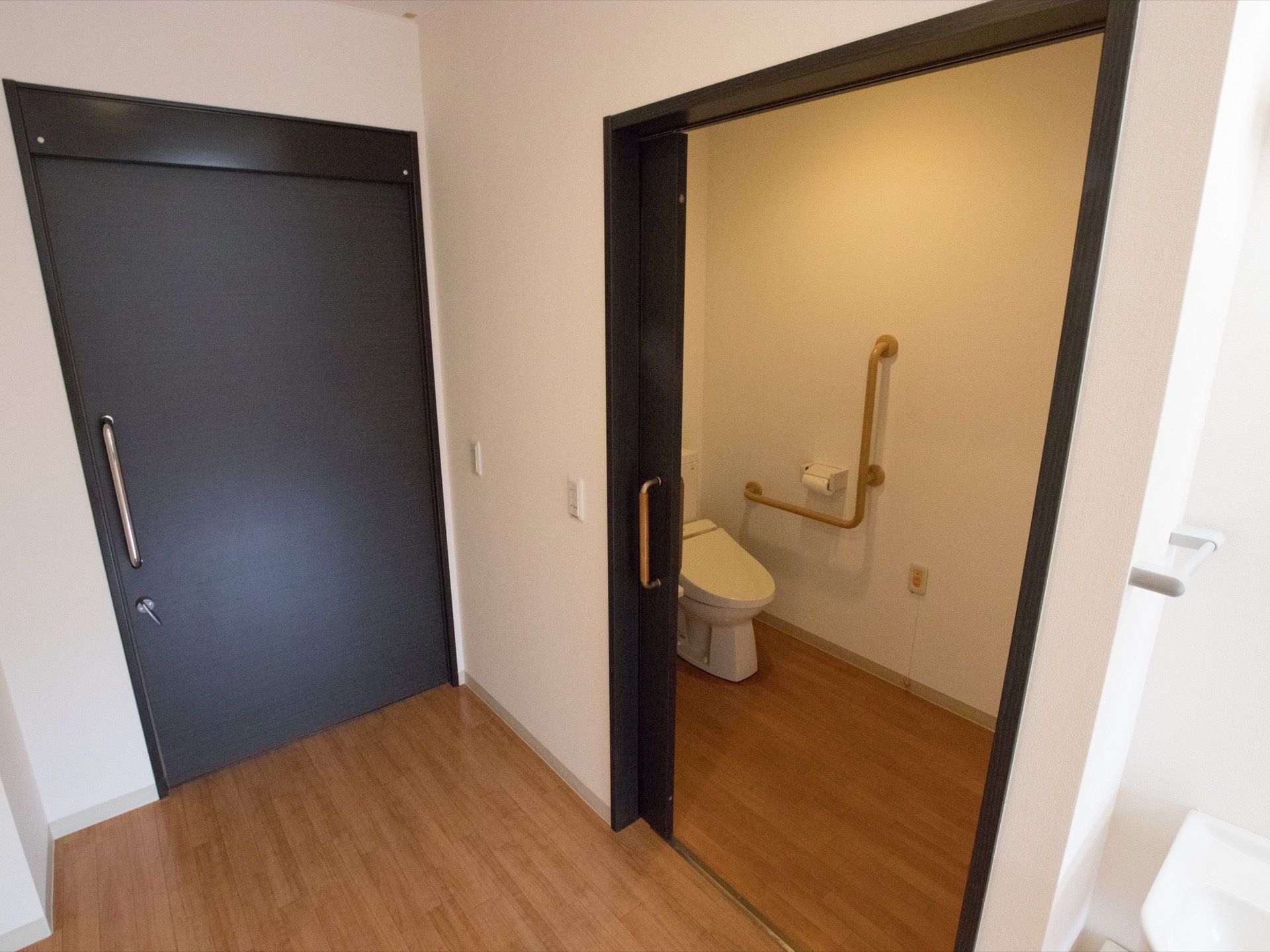 居室に入ると左手に引き戸があり、中はトイレになっている。トイレの入口横に、トイレの照明と室内の照明のスイッチがある。