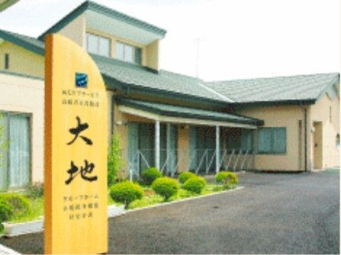 黒字で大地の字を書かれた木製の看板が置かれた窓の多い二階建ての建物