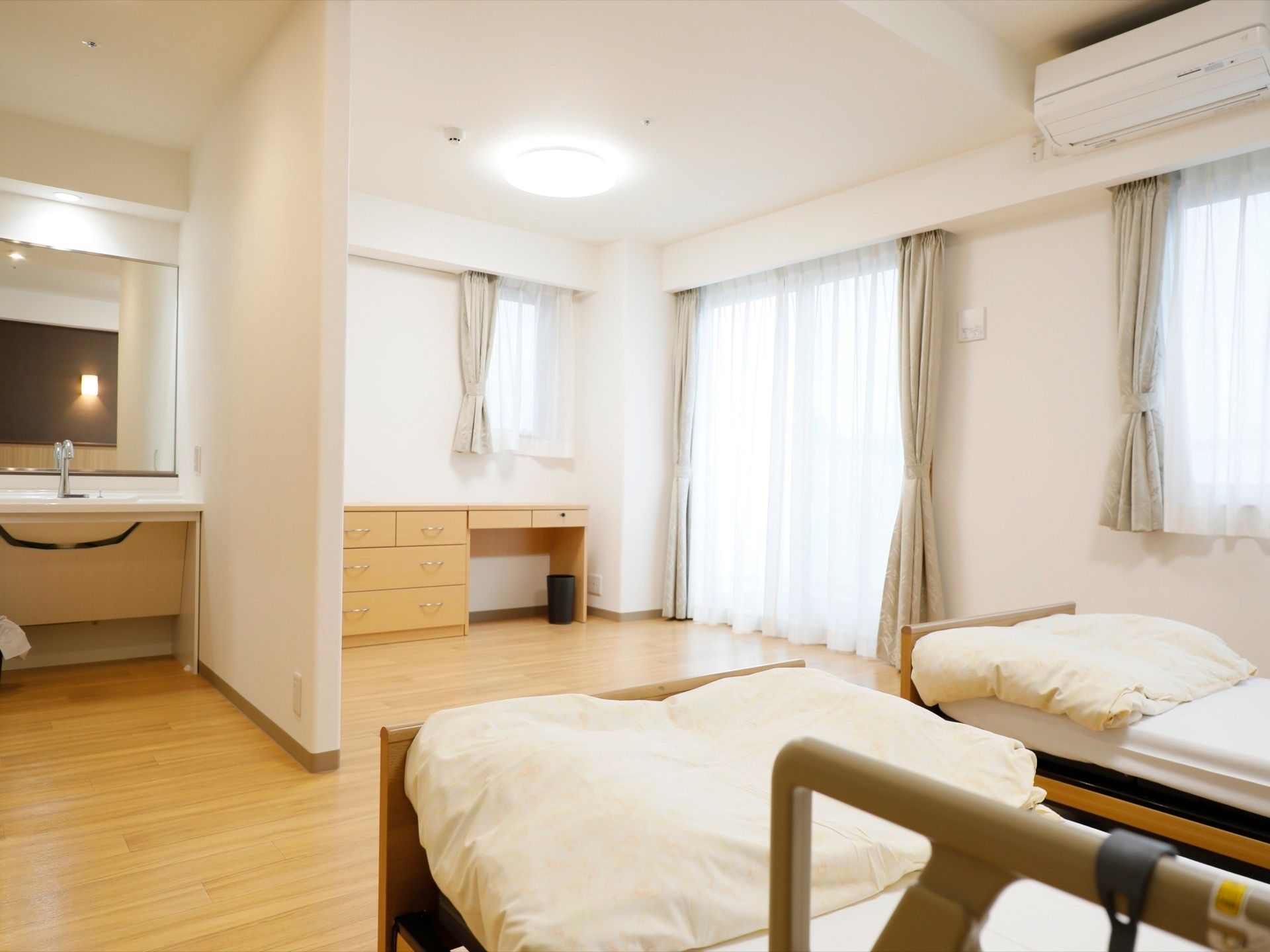 陽の光がよく入る居室になっている。ベッドが２つあり、部屋には収納スペースや、手洗い場も設けられている。