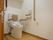 よく清掃のなされたトイレである。便座には肘掛けが取りつけられており、壁には手すり、非常用ベルも設置されている。