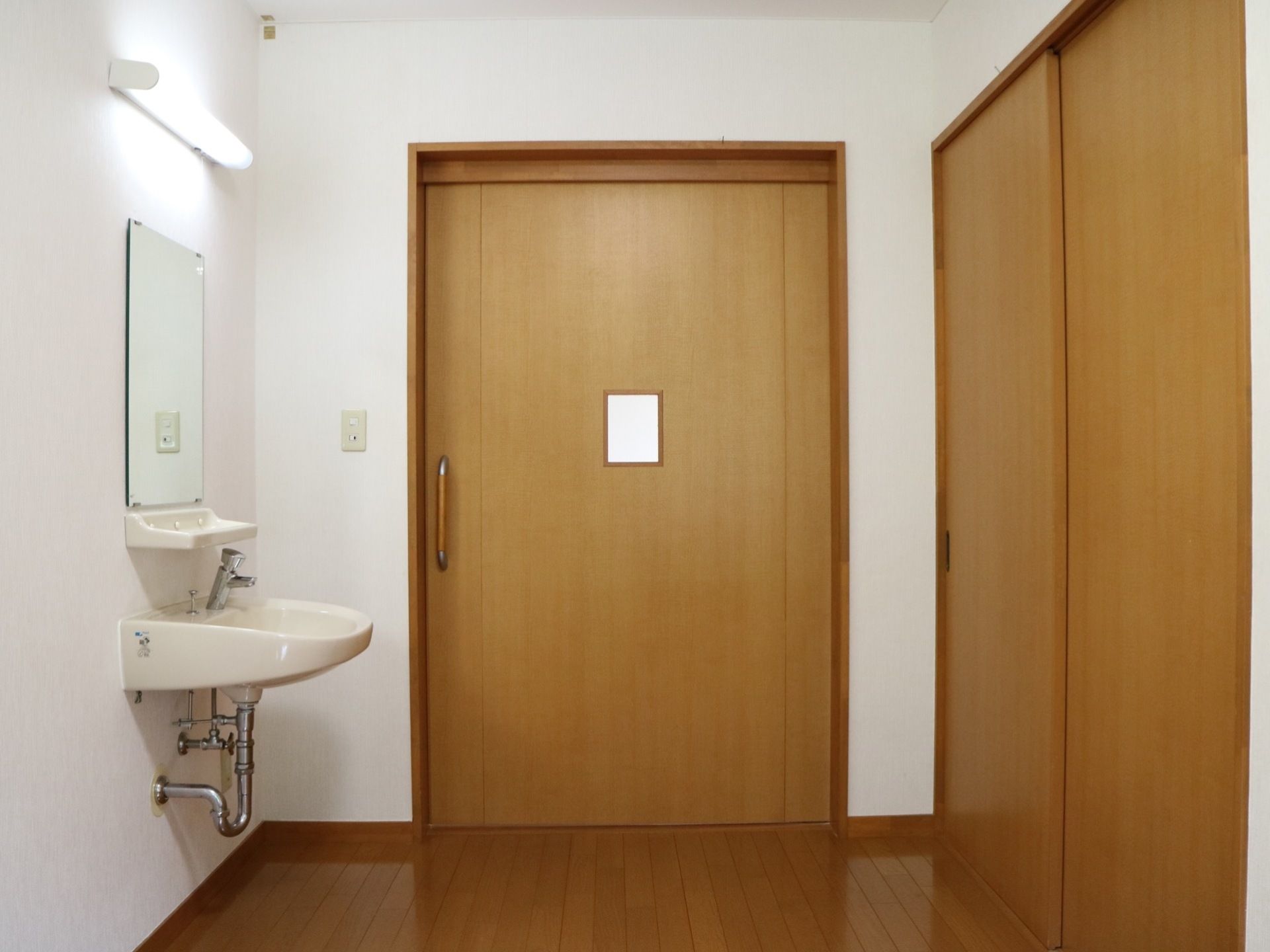 フローリングの個室である。収納が設けられており、引き戸になっている。洗面台が併設されており、鏡が取り付けられている。
