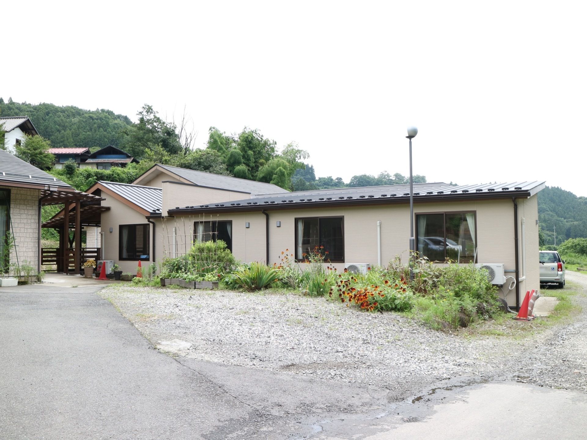 落ち着いた雰囲気の施設外観である。平屋建ての建物になっており、敷地内には季節に応じた花が植えられている。
