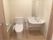 引き戸をあけるとトイレと洗面台がある。白を基調とした空間で清潔感ただよう。トイレ両側に手すりが設置されている。