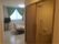 バリアフリー設計の居室。トイレと洗面台つき。白っぽい床にベッド、テレビが置かれている。グリーン系のカーテンが目を引く。