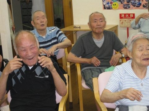 椅子に座った数名の男性が楽しそうに身体を動かしている様子