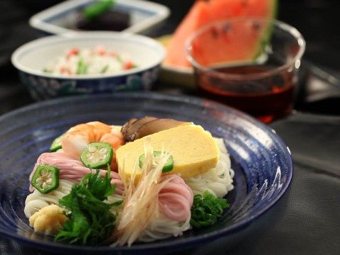 オクラや卵焼き等具材ののったそうめんとスイカの夏らしい食事