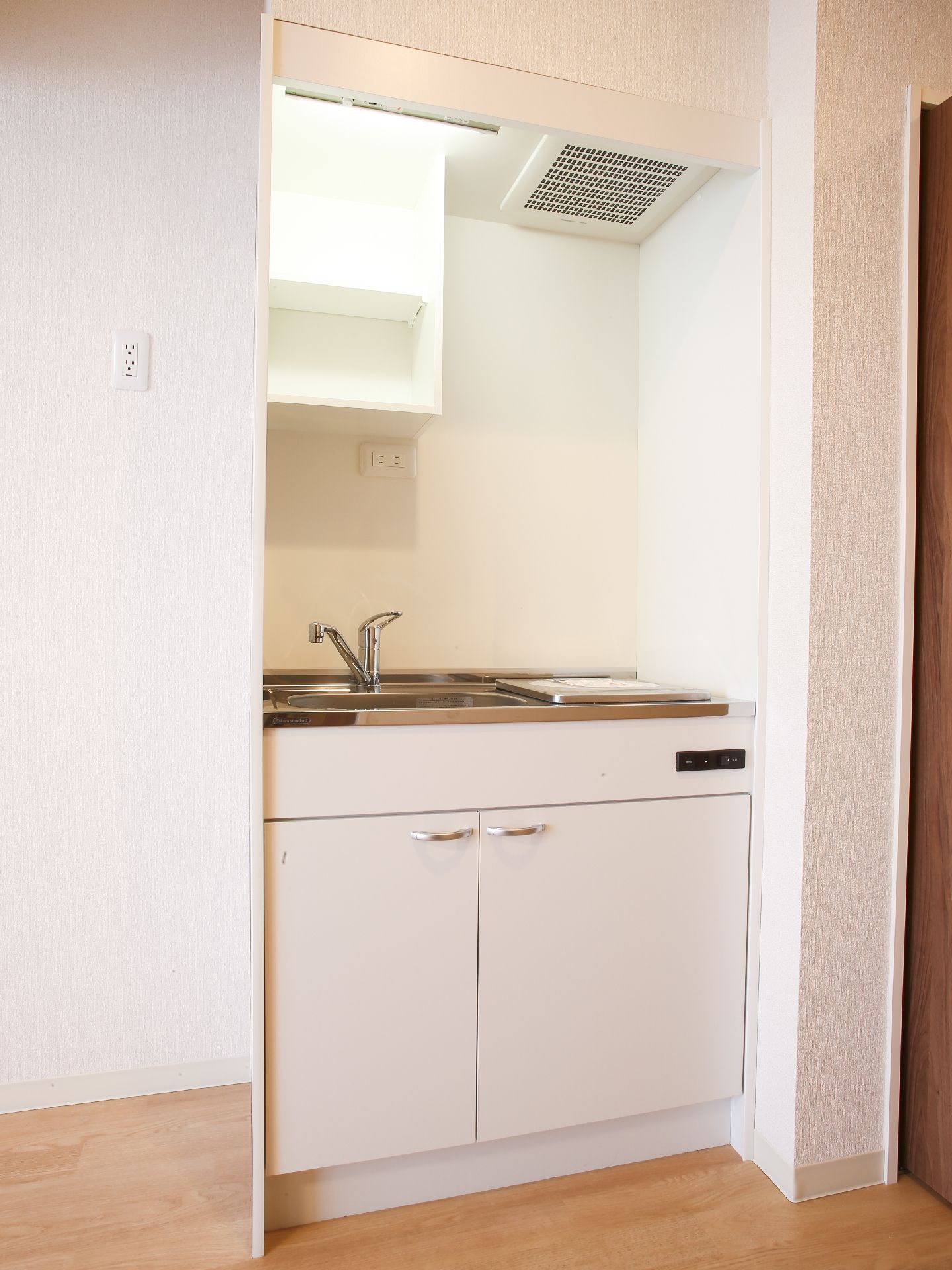 白を基調とした清潔な室内には簡易キッチンがある。棚や換気扇、電磁調理器が付いていて、蛇口はレバーハンドル式で開閉が便利。