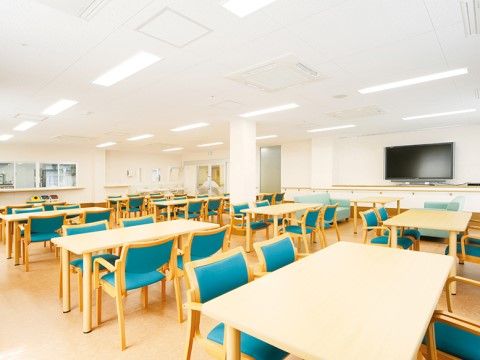 大きなテレビ１台と４人掛けのテーブルが沢山並んだダイニング