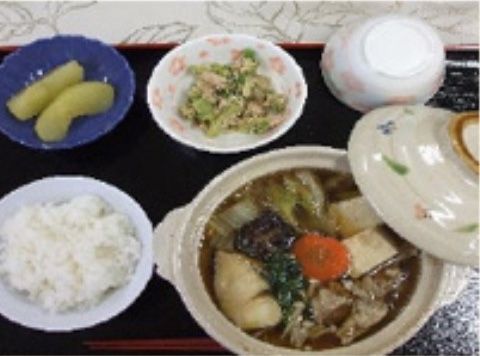 ご飯、小鍋のメイン料理、小鉢２種類、湯飲み茶わんが乗せられたお盆
