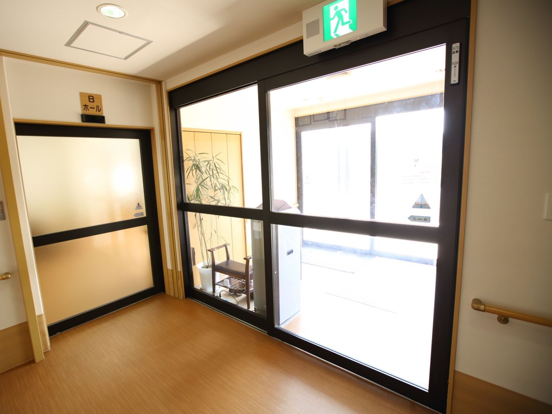 大きなガラス張りの自動ドアが玄関に設置されている。周りの壁には手すりがあり、つかまりながら移動することができる。