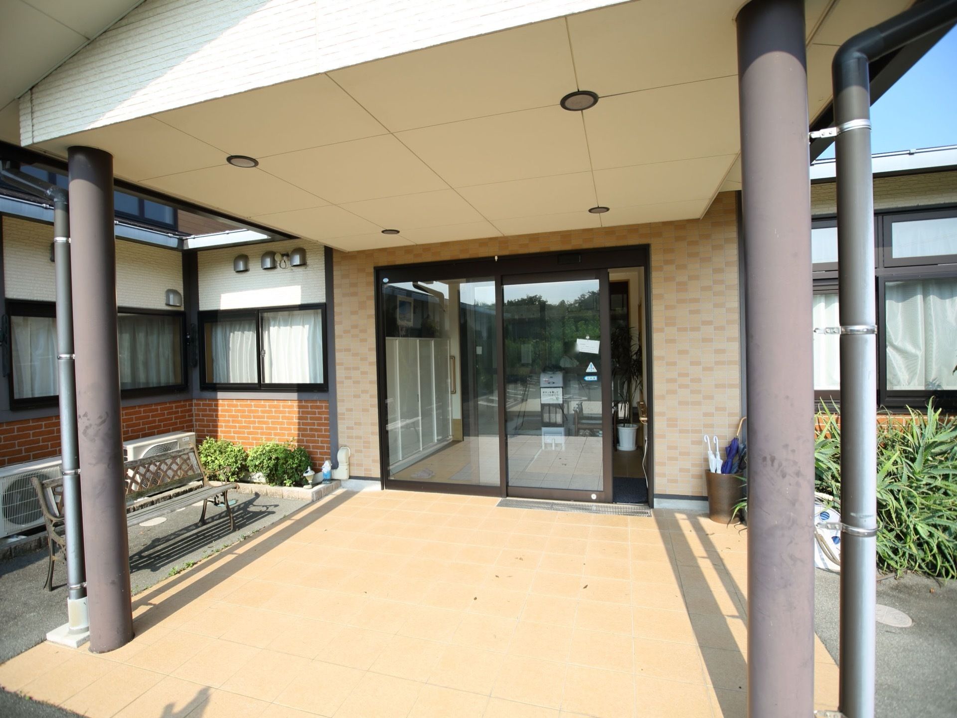 玄関の前には大きな屋根の付いた広いスペースがある。ベンチに座ってくつろぐことができる。扉の脇には傘立てが置かれている。