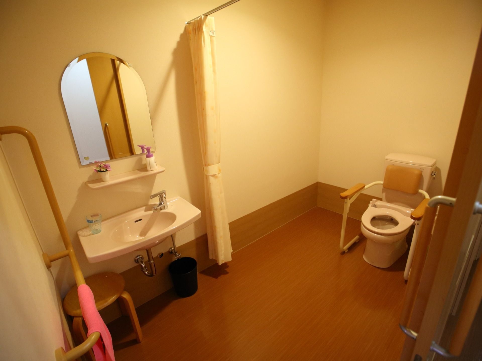 ベージュ色を基調とし、広いスペースを確保したトイレである。洗面台があり、レバー式の水栓になっている。