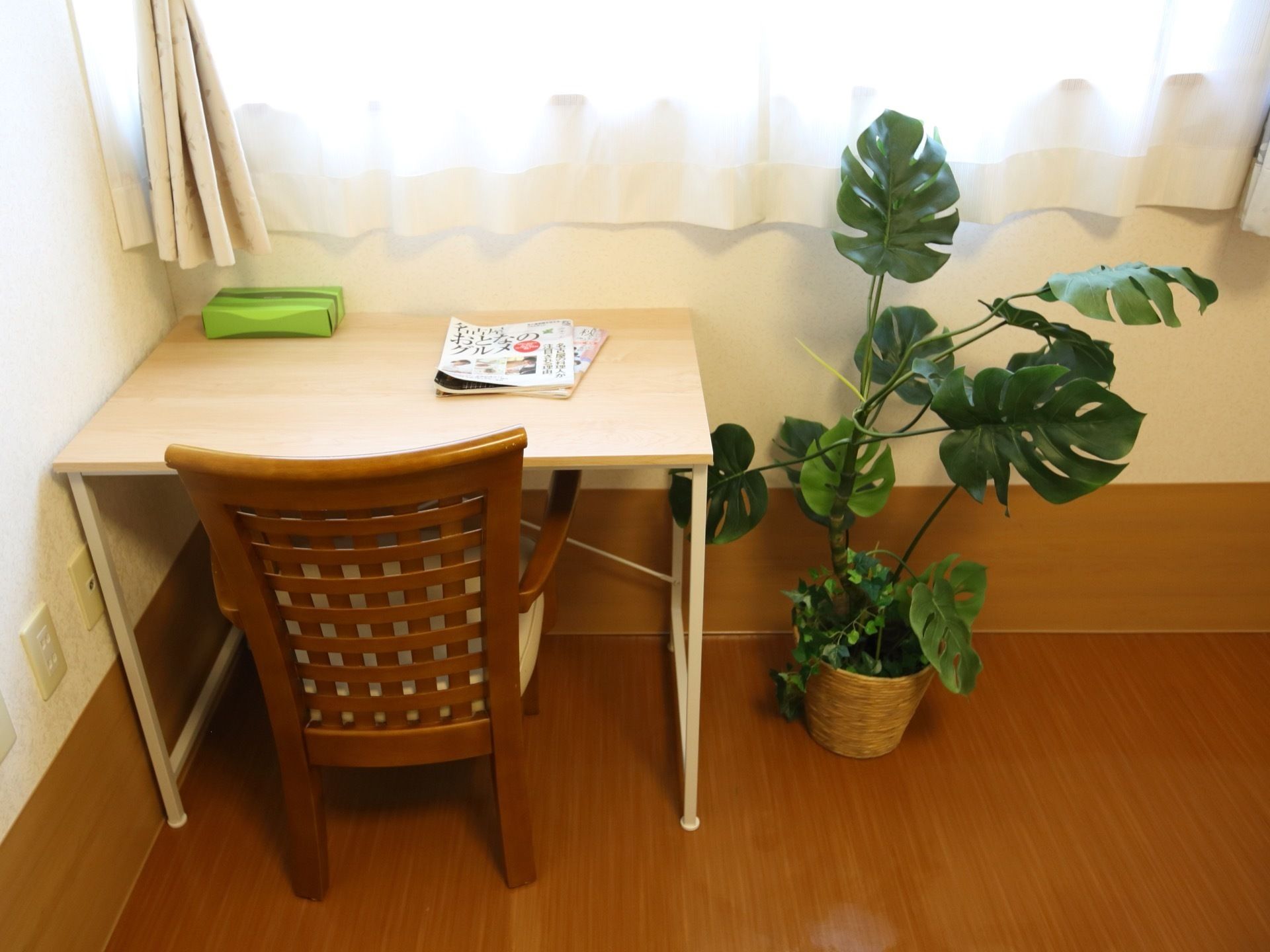 居室の窓際に椅子とテーブルが設置されている。テーブルの脇には観葉植物が置かれている。読書などを楽しむことができる。