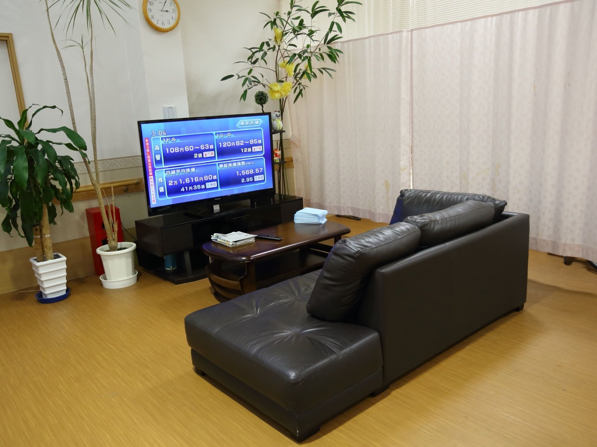 黒色のソファやテレビなどを設置した共有スペースである。テレビの脇には背の高い観葉植物が置かれている。