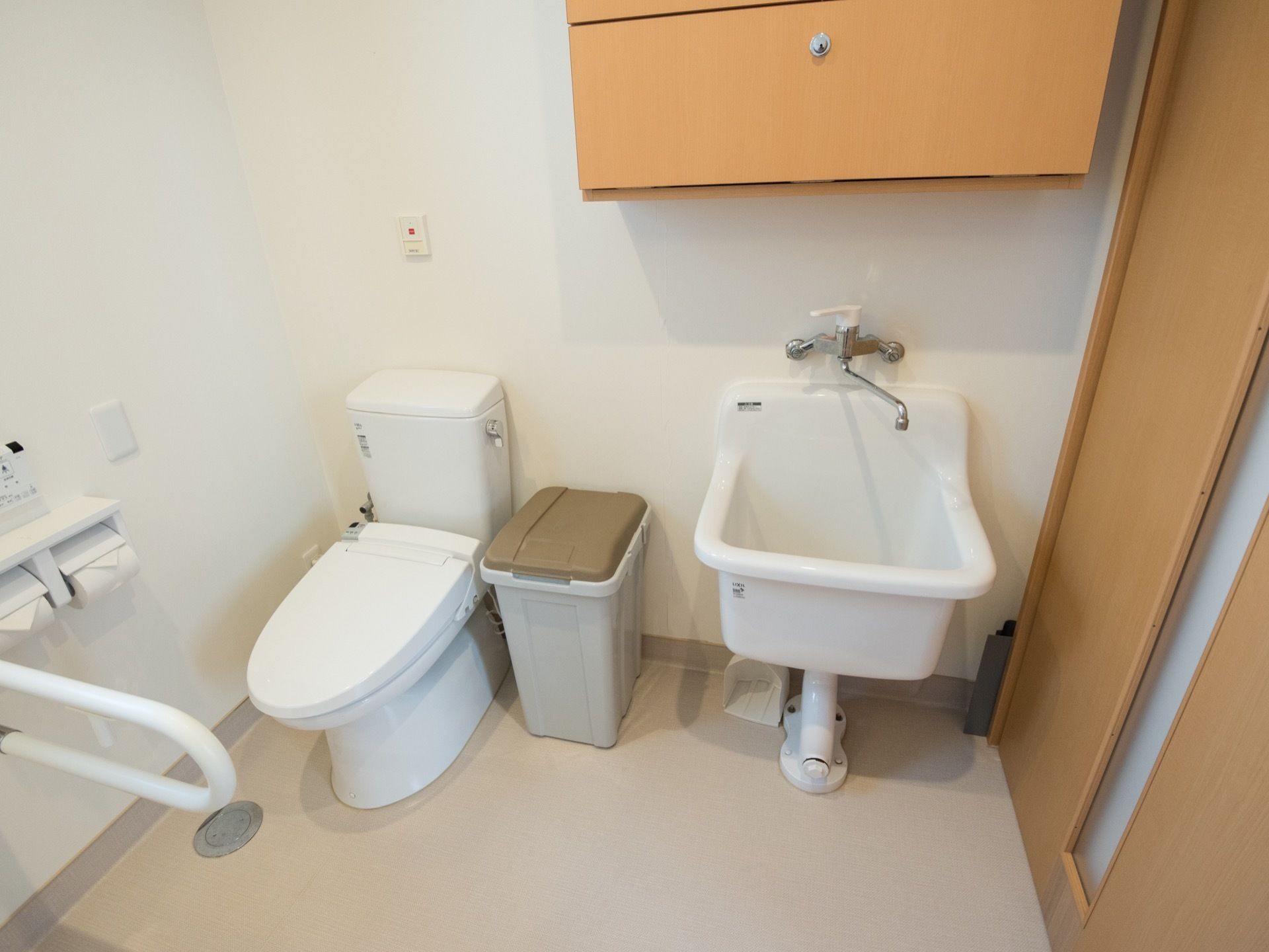 オストメイト対応のトイレが完備されている。洋式便座のとなりにゴミ箱が置かれてある。収納家具も設置されている。