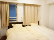 居室のベッドルーム。二人部屋であり、二台のベッドが並んで設置されている。窓は網入りタイプで、カーテンが付いている。