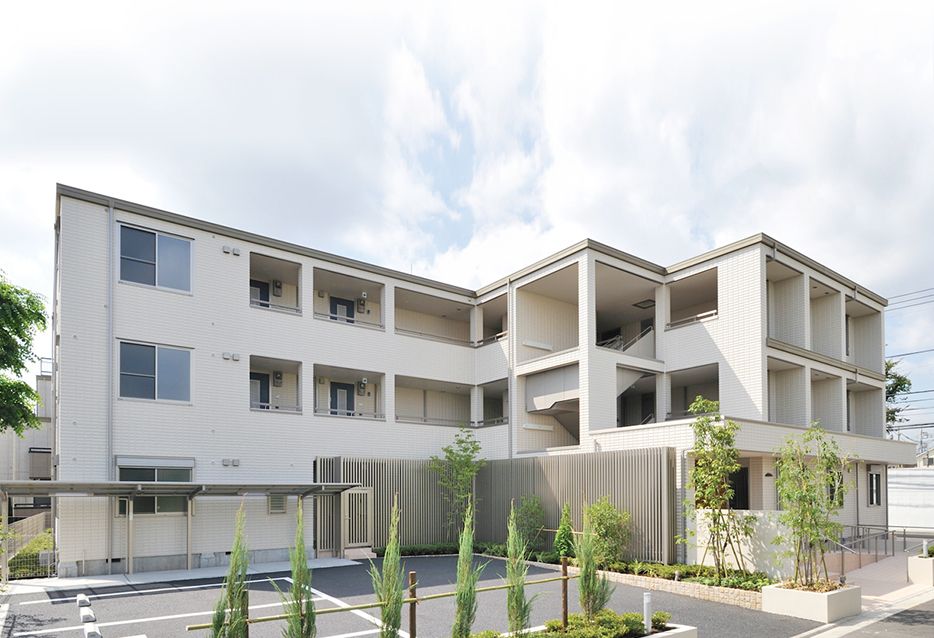 3階建ての白い建物と駐車場