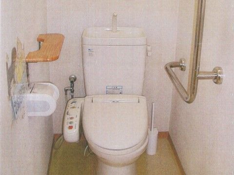 トイレは白い壁で、明るく清潔感のあるスペースである。手すりを設置しており、体を支えながら利用することができる。