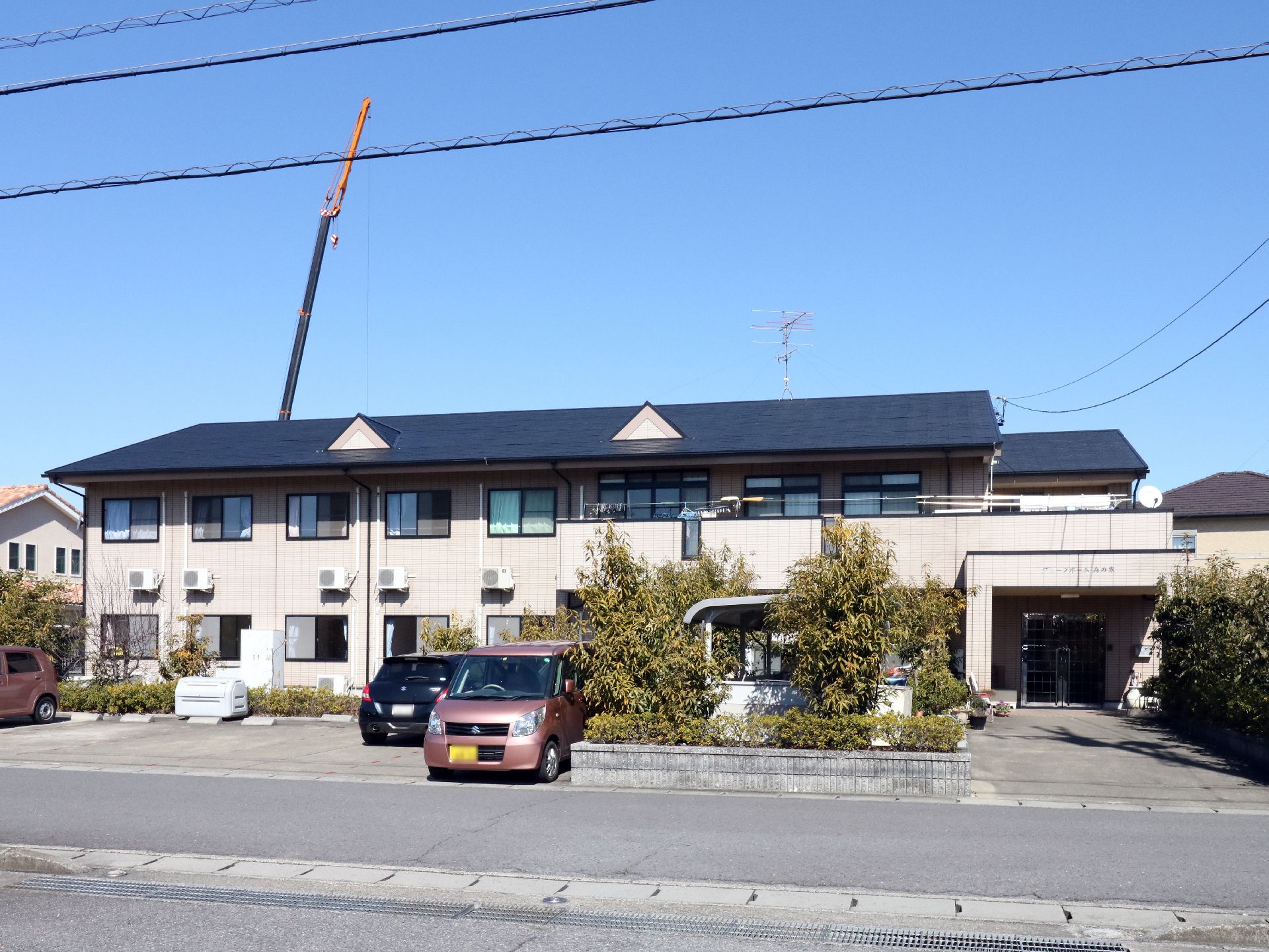 明かり取りの小さな屋根が２つ付いた、２階建ての施設と駐車場