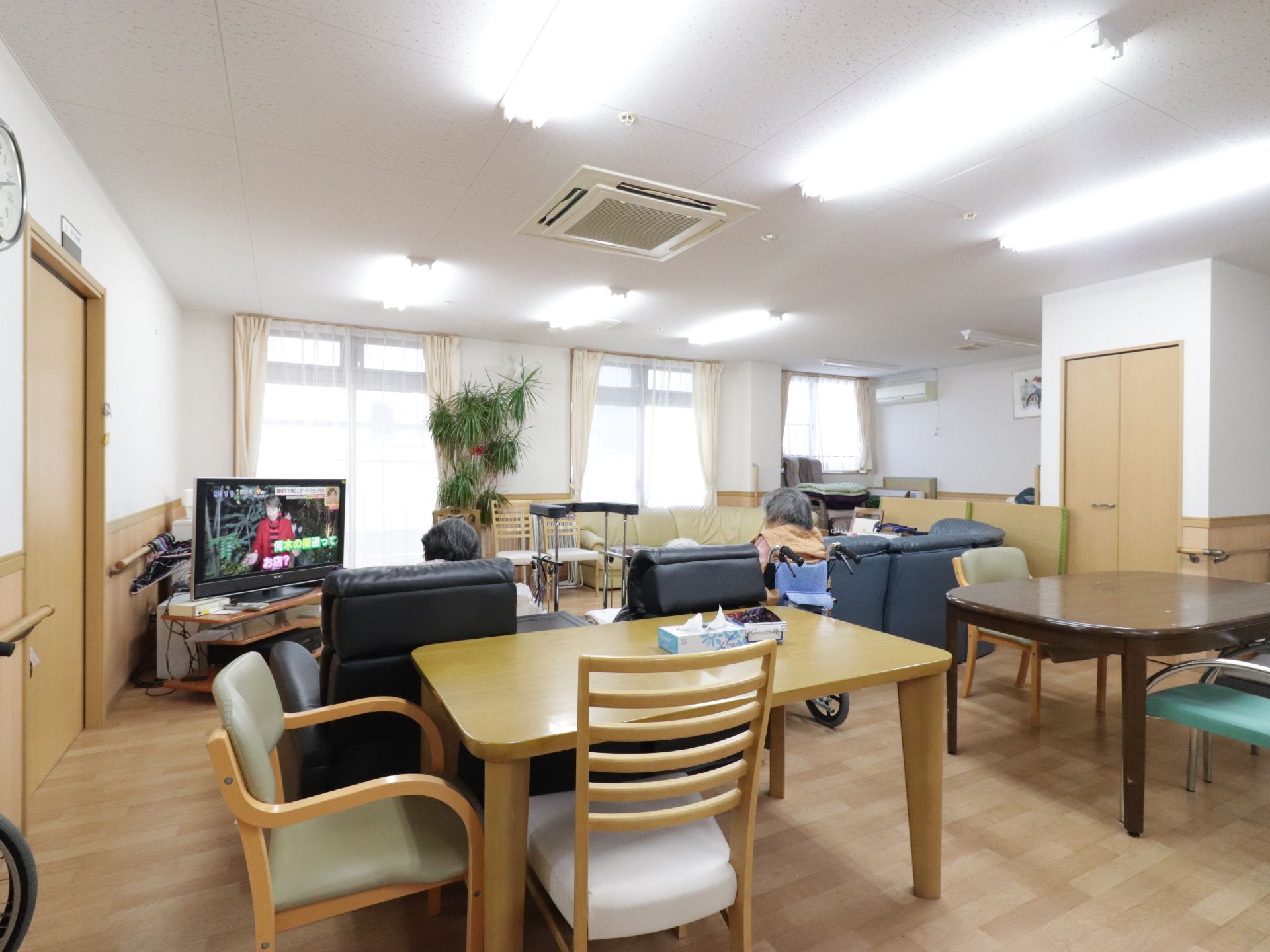 窓際に大型テレビがあり、それを取り囲むようにさまざまなソファーが並べられている。歩行器が真ん中あたりに置いてある。