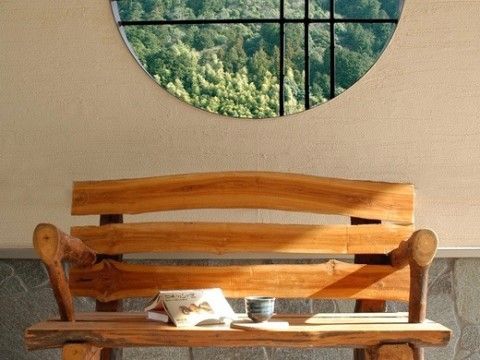 円形の窓からは木々が見え、木材を使用したベンチの上にはお茶と本がおいてある場所