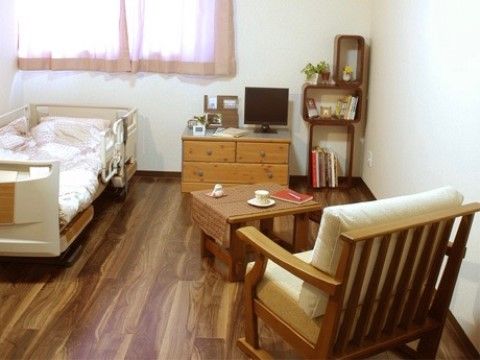 出窓があり、介護用のベッドとテレビ、木目調の本棚が設備されている居住空間