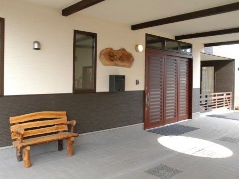 スライド式のドアの出入り口があり、看板やベンチは木材を使用されている玄関