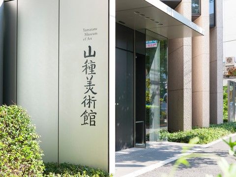 オフィスビルのような建物で、壁には美術館の名前が書かれている。建物の周辺には、樹木が植えられている。