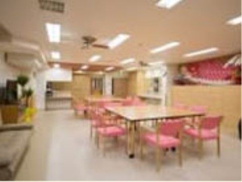 広いスペースに、ピンクの椅子が多数配置された大きな四角いテーブルが２台ある食堂