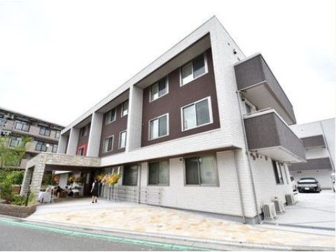３階建てで、壁面が白を基調に一部焦げ茶色でアクセントをつけたデザイン性のあるボックス型建物の外観