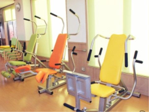 シートが黄色、オレンジ、草みどりの色違いで３台、トレーニングマシーンが並んで置いてある機能訓練室