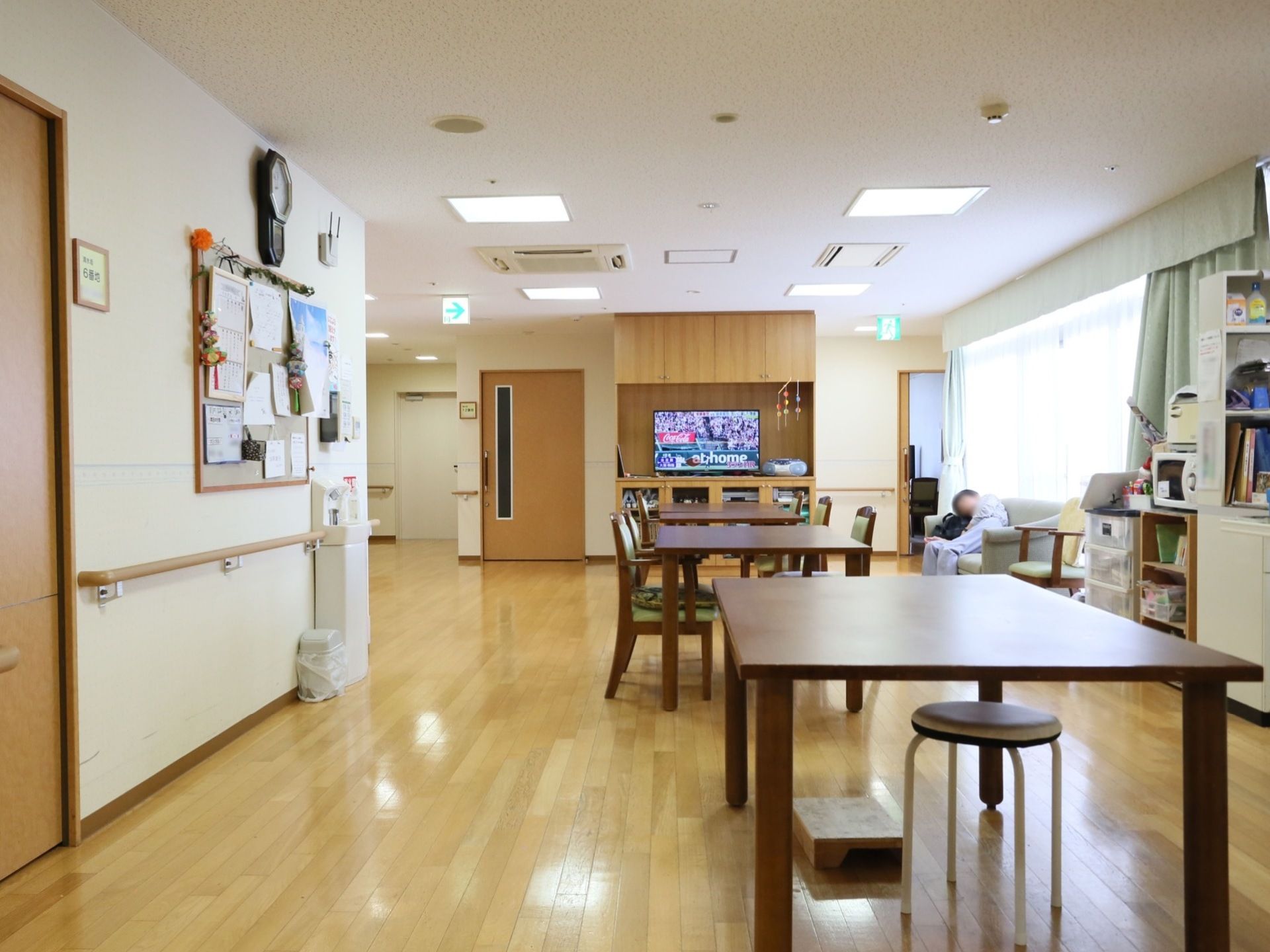 テレビやソファ、ダイニングテーブルのあるアットホームな共有スペース。壁には施設に関する掲示物があり、施設の情報発信の拠点になっている。