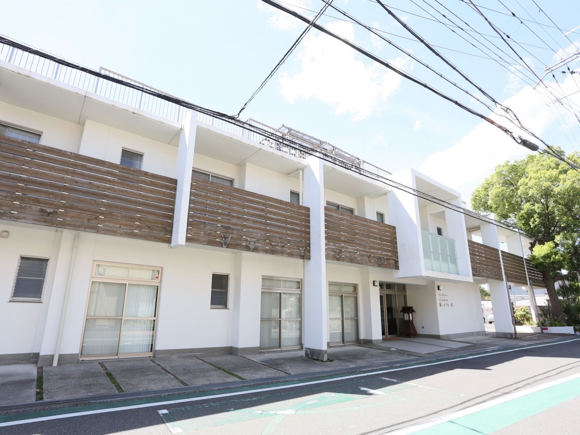 真っ白な建物のアクセントになる木目のバルコニーは、リゾートマンションを思わせる。外部からの視線を遮れるよう、柵はは高めに作られている。