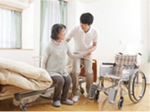 ベッドから車椅子に移る際にスタッフの介助を受ける女性
